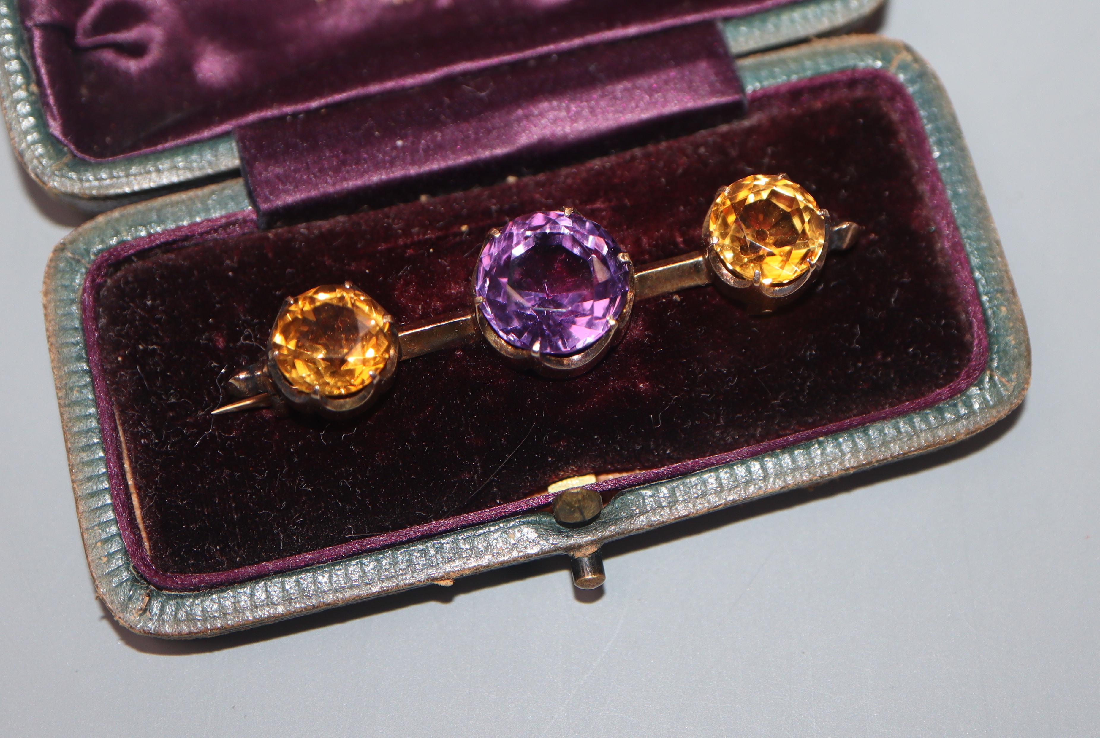 An early 20th century yellow metal, amethyst and citrine three stone bar brooch, 52mm.