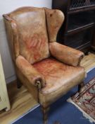 A faded red / brown leather wing armchair