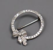 A mid 20th century white metal and diamond set openwork circular brooch with ribbon bow motif,