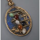 A yellow metal and multi gem set mounted lapis lazuli set oval pendant, on an early 20th century