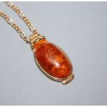 A 9ct yellow gold-mounted oval amber pendant on yellow metal chain (tests as 9ct)