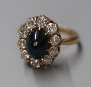 A Finnish 585 yellow metal, cabochon sapphire and diamond set oval cluster ring, size N/O.