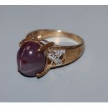 A 9k yellow metal and cabochon star ruby dress ring, with diamond chip set shoulders, size N.