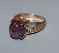 A 9k yellow metal and cabochon star ruby dress ring, with diamond chip set shoulders, size N.