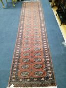 A red ground Bokhara style runner 320 x 78cm