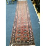 A red ground Bokhara style runner 320 x 78cm