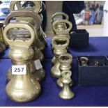 A set of eleven brass bell-shaped weights and another similar large weight