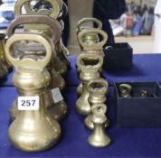 A set of eleven brass bell-shaped weights and another similar large weight