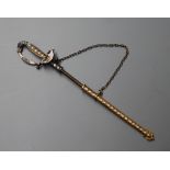 A yellow and white metal, enamel and seed pearl set jabot pin, modelled as a sword with scabbard,