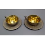 A pair of Soviet textured 875 white metal tea cups and saucers.