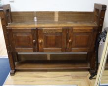 A small oak 'cheese press' bookcase, the cupboard enclosed by three doors W.150cm