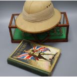 A cased cast lead marching soldier's pith helmet and The Wonder Book of Soldiers