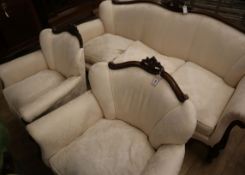 An early 20th century French carved mahogany three piece suite, upholstered in ivory damask