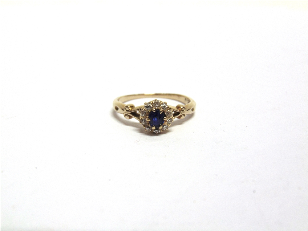 A SAPPHIRE AND DIAMOND CLUSTER RING the yellow split shoulder shank stamped '18ct' and 'H&Co', the