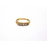 A DIAMOND RING stamped '18ct', set with four graduated old brilliant cuts and one setting vacant,