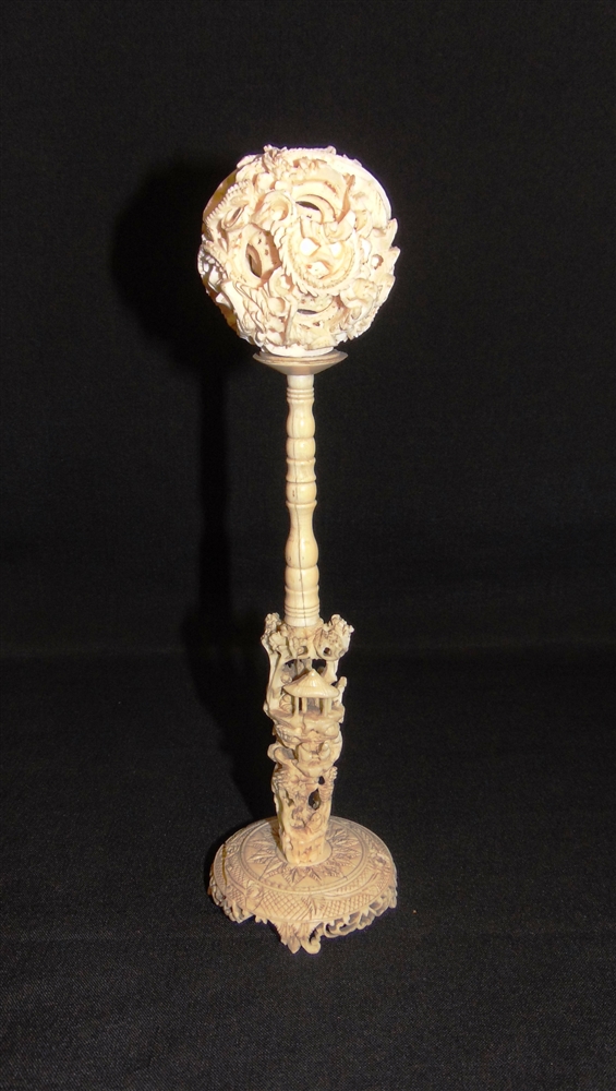 A CHINESE IVORY PUZZLE BALL ON STAND late 19th or early 20th century, the dragon entwined outer ball