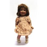 A COMPOSITION DOLL possibly Italian, with a brown wig and 'flirty' eyes, and a peach satin outfit,
