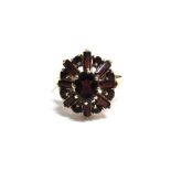 A 9CT GOLD AND GARNET CLUSTER RING centred with an oval garnet within a baguette and round garnet