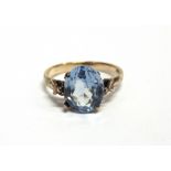 A PALE BLUE SYNTHETIC-SPINEL SINGLE STONE RING the oval mixed-cut stone claw set in yellow metal