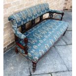 AN EDWARDIAN WALNUT FRAMED SOFA with pierced and carved uprights, on turned supports, 146cm wide