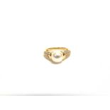 A CULTURED PEARL AND DIAMOND 18 CARAT GOLD RING the 8.2mm diameter pearl between shoulders each