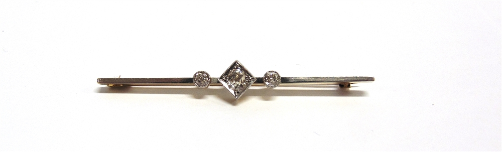 AN EARLY 20TH CENTURY GOLD AND DIAMOND THREE STONE BAR BROOCH the central cushion-shaped old-cut