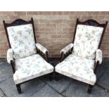 A PAIR OF EDWARDIAN UPHOLSTERED ELBOW CHAIRS the top rails carved with a flower head, the arms