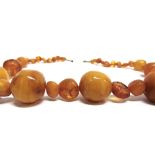 AN EARLY 20TH CENTURY AMBER NECKLACE the graduated off-round and baroque beads of varied colour