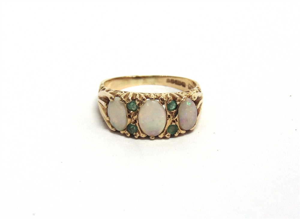 A 14CT GOLD, OPAL AND EMERALD DRESS RING the three graduated oval white opal cabochons spaced by