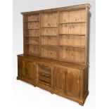 A LARGE STAINED PINE BOOKCASE/DRESSER the upper section with three bays of adjustable shelves, the