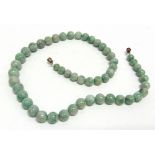 A JADEITE BEAD NECKLACE the light-green mottled round beads graduated approx. 12.1mm to 7.5mm,