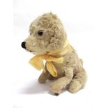 AN ALPHA FARNELL CREAM PLUSH MUSICAL SOFT TOY DOG in seated pose, with orange glass eyes and wood-