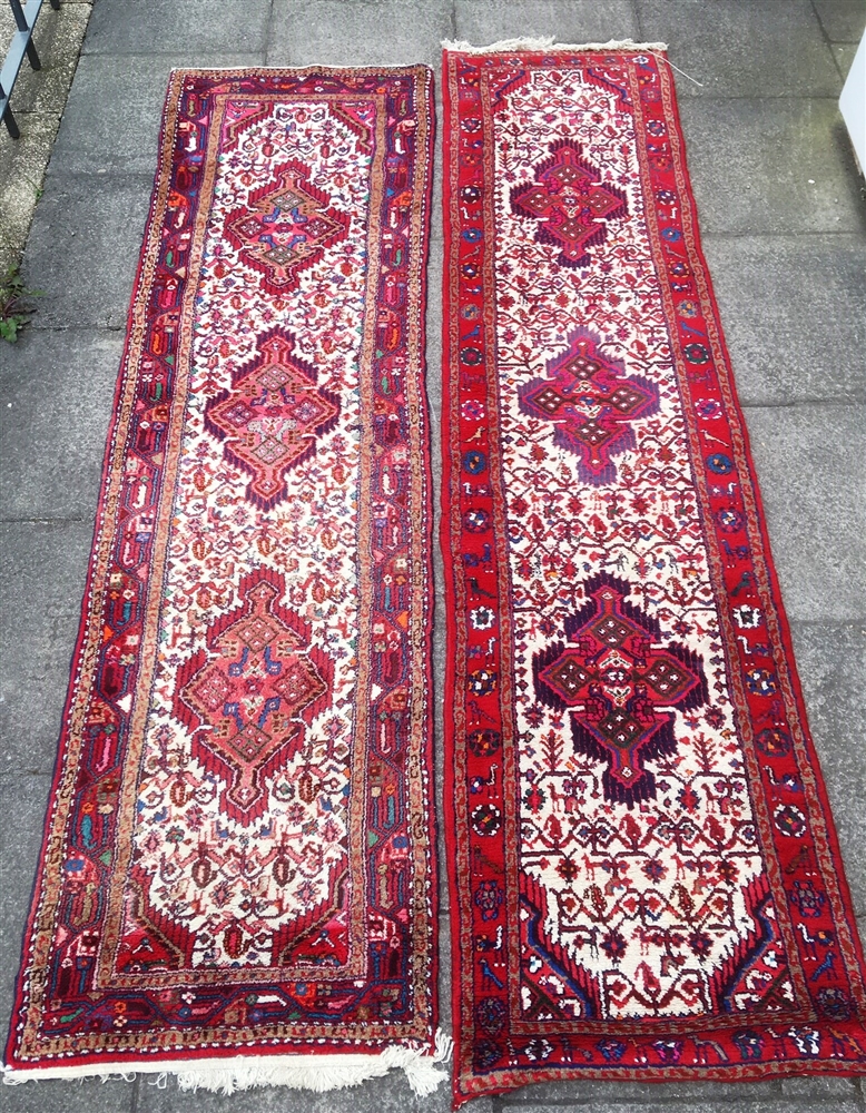 TWO RED GROUND RUNNERS each with three hooked medallions to the central field, 85cm x 293cm and 73cm