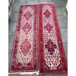 TWO RED GROUND RUNNERS each with three hooked medallions to the central field, 85cm x 293cm and 73cm
