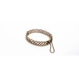 AN EARLY 20TH CENTURY ROSE GOLD HOLLOW HINGED BANGLE of hollow entwined polished and rope-twist