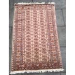 A RED GROUND RUG the central field with three rows of guls (faded), 200cm x 124cm