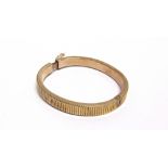 AN EARLY 20TH CENTURY ROSE GOLD HOLLOW HINGED BANGLE of hollow reeded-rectangular section, on a