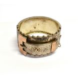 A LATE VICTORIAN SILVER BROAD 'BUCKLE' BANGLE the front with gilt accents, part foliate engraving