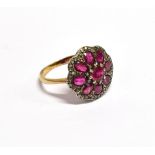 A RUBY AND DIAMOND FLOWER-HEAD CLUSTER RING with a central round mixed-cut ruby within an octofoil