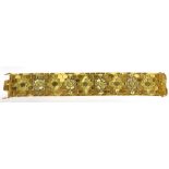 AN ITALIAN BI-COLOUR GOLD 'HONEYCOMB' BROAD BRACELET engraved with flowers and leave within