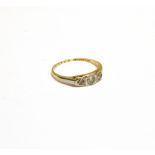 AN EARLY 20TH CENTURY GOLD AND SMALL DIAMOND THREE STONE RING the graduated round-brilliant and