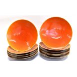 ELEVEN LARGE CERAMIC CHARGERS with orange lustre glaze, 33cm diameter