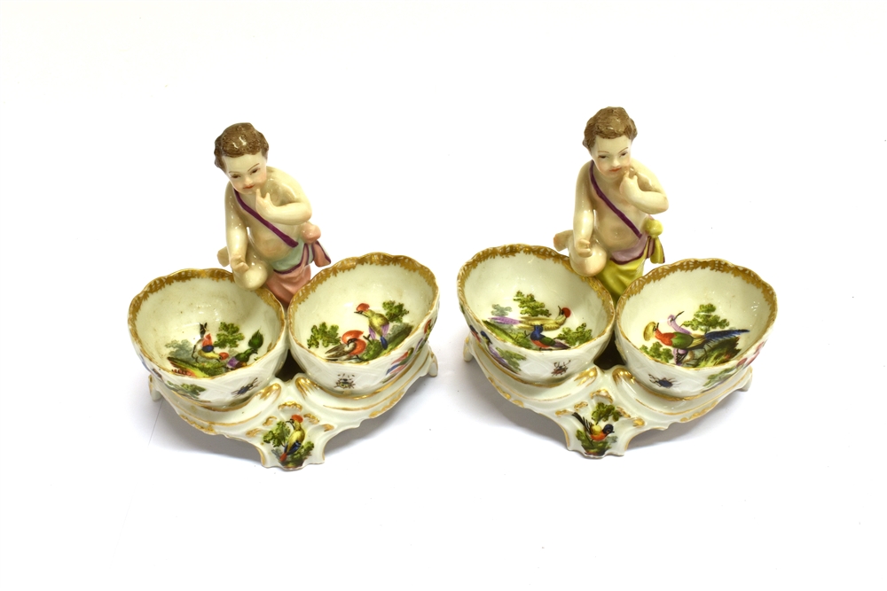 A PAIR OF POLYCHROME ENAMELLED FIGURAL SALTS the bowls decorated with birds and insects,