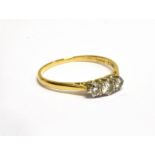 AN EARLY-MID 20TH CENTURY GOLD AND DIAMOND THREE STONE RING the graduated round brilliants approx.