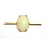 AN EARLY 20TH CENTURY GOLD AND OPAL BAR BROOCH the oval cabochon white opal displays a mostly