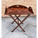 A GEORGE III MAHOGANY BUTLERS TRAY of oval form with brass hinged fold-down sides, 100cm x 75cm in