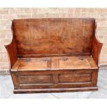 A GEORGE III ELM BOX SETTLE the seat with two hinged lids, two fielded panels to the front, 127cm