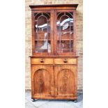 A WILLIAM IV MAHOGANY BOOKCASE the upper section with arched glazed doors enclosing adjustable