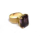 AN ORIENTAL YELLOW METAL AND RECTANGULAR AMETHYST SINGLE STONE RING the step-cut stone approx. 15.