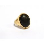 AN ORIENTAL YELLOW METAL AND OVAL-CABOCHON BLACK ONYX SINGLE STONE RING on a tapering shank